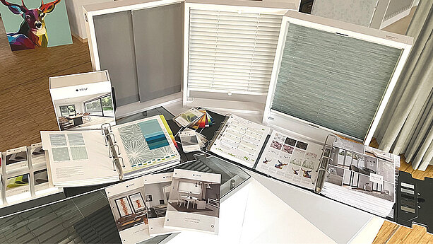 Tisch mit ausgebreiteten MHZ-Musterkollektionen, Farbfächern und Informationsmaterialien zu Sonnenschutzprodukten