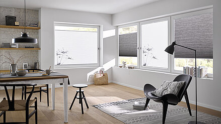 Wohn- und Essbereich mit weissen und grauen Wabenplissees, teilweise mit floralem Druckmotiv, als Sicht- und Wärmeschutz