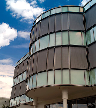 Gebäude mit gerundeter Glasfassade und mehreren ZIP-Senkrechtmarkisen zur Beschattung.