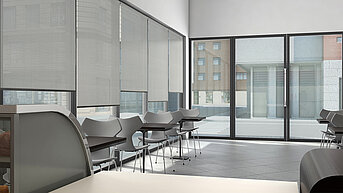 Innenaufnahme eines Cafés mit MHZ-Rollos aus Serge Ferrari-Gewebe an den Fenstern und modernen Stühlen und Tischen.