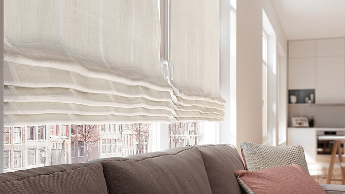 Detailansicht eines beigen Raffrollos mit sanften Wellen über einem Wohnzimmersofa bei Tageslicht