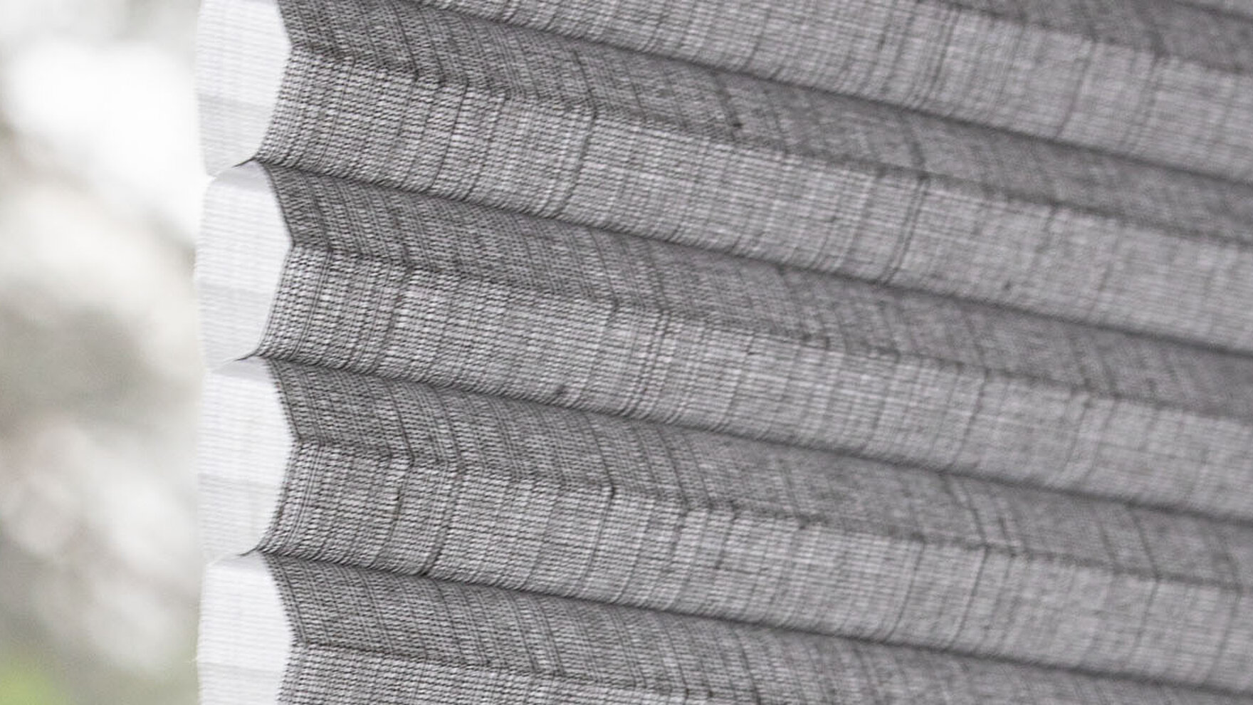 Seitliche Nahaufnahme eines grauen MHZ Wabenplissees mit klar erkennbarer Zellstruktur.