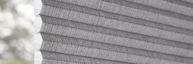 Seitliche Nahaufnahme eines grauen MHZ Wabenplissees mit klar erkennbarer Zellstruktur.