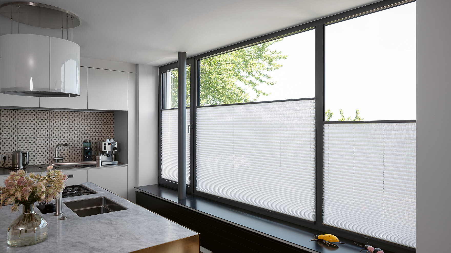 Weisse Plissees im unteren Fensterbereich in moderner Küche mit grossen Fensterflächen.